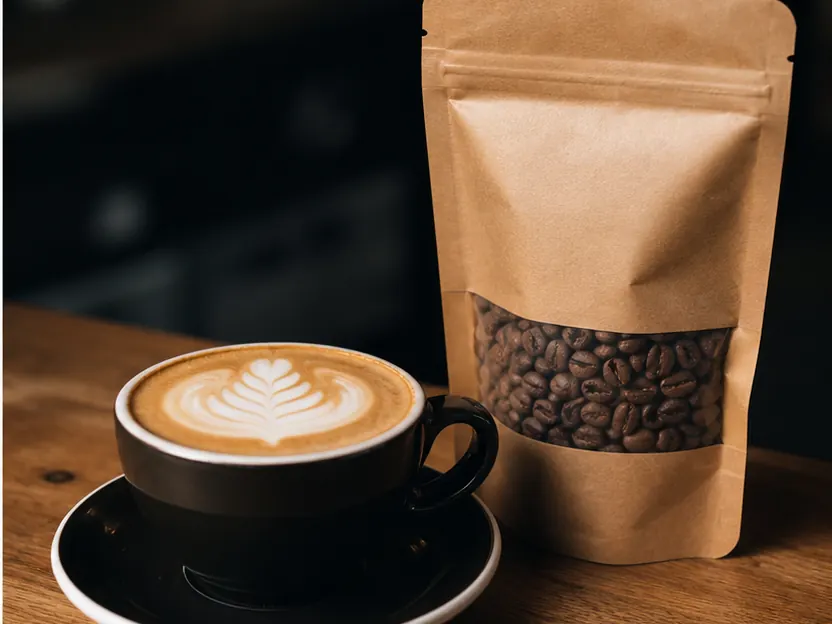 Detail cappuccina a balení pražené kávy, ilustrační fotografie KIKAFE Ostrava