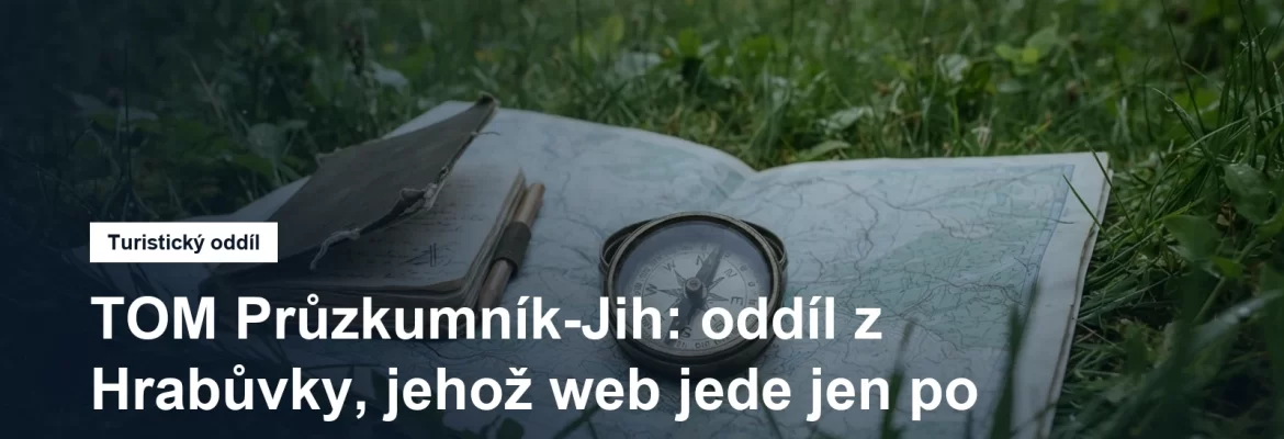 Buzola a zápisník na mapě rozložené v trávě