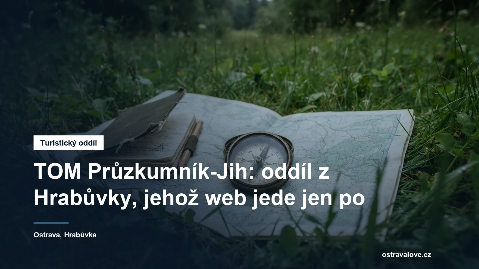 Buzola a zápisník na mapě rozložené v trávě