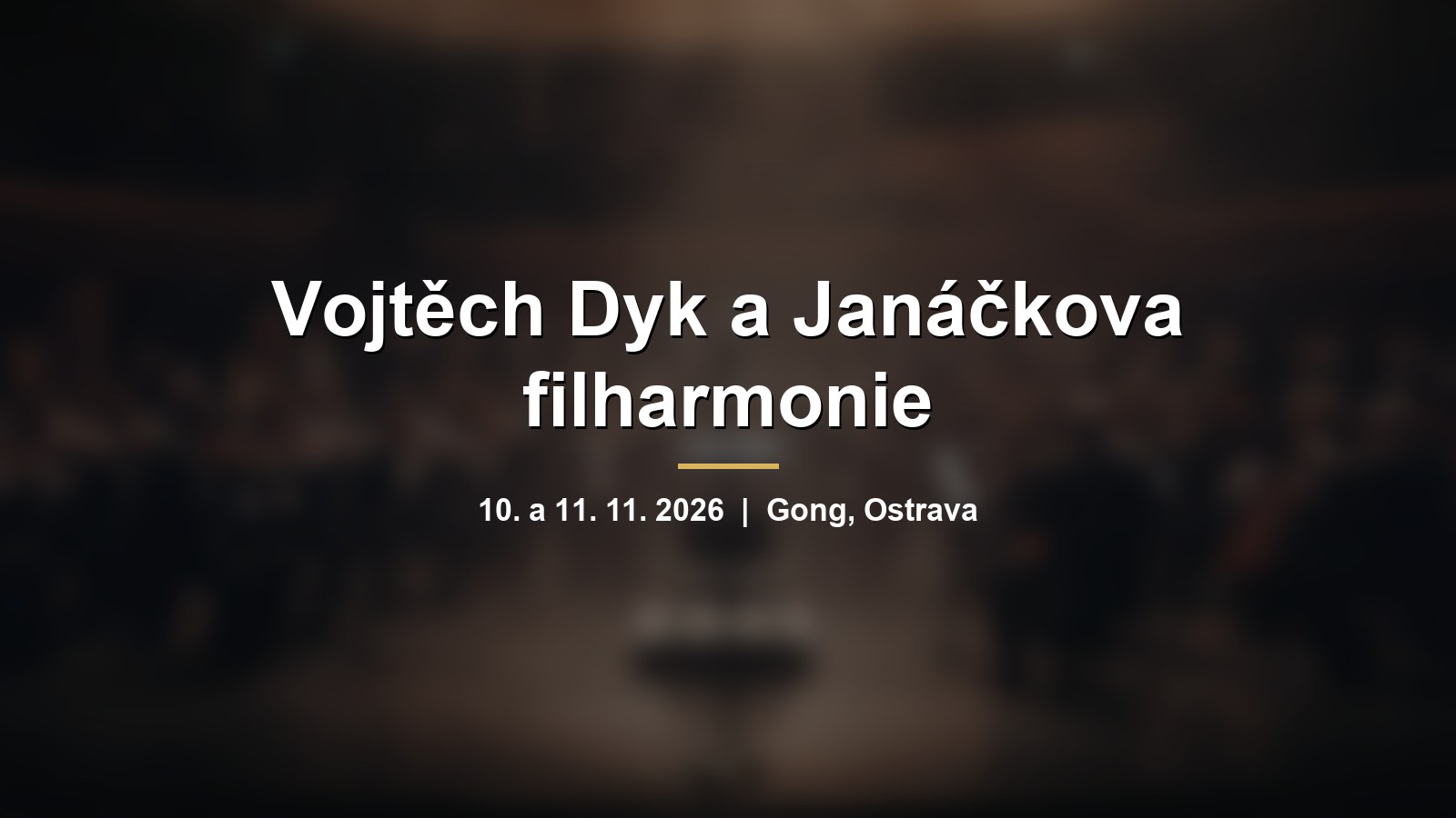 Rozmazaný symfonický orchestr na pódiu s nápisem Vojtěch Dyk a Janáčkova filharmonie
