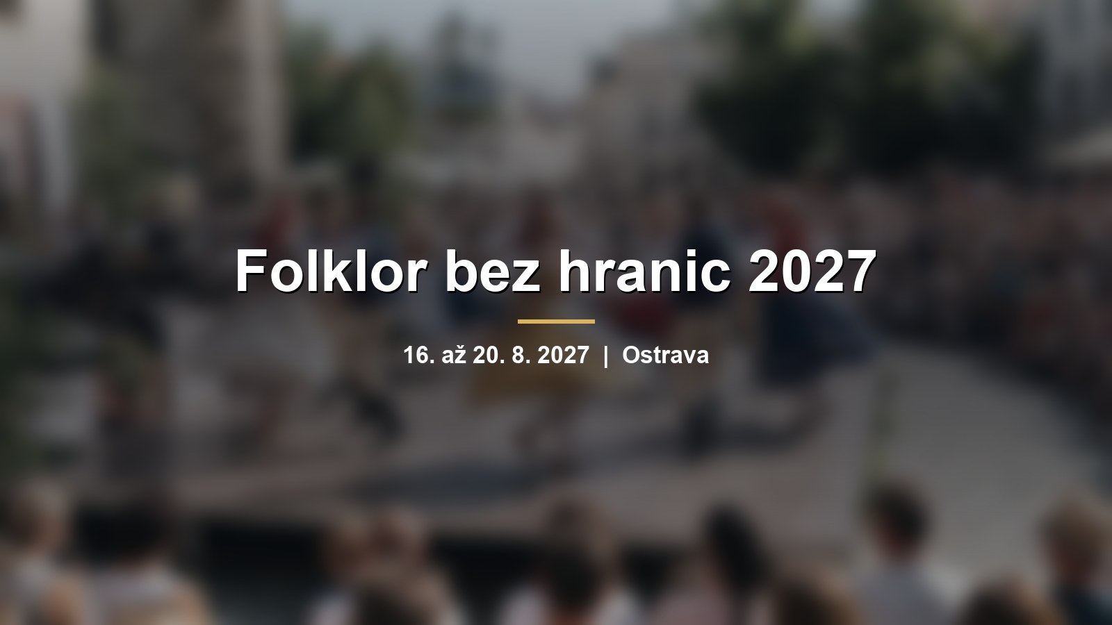 Rozmazaní tanečníci v barevných krojích na letním pódiu na náměstí s nápisem Folklor bez hranic 2027