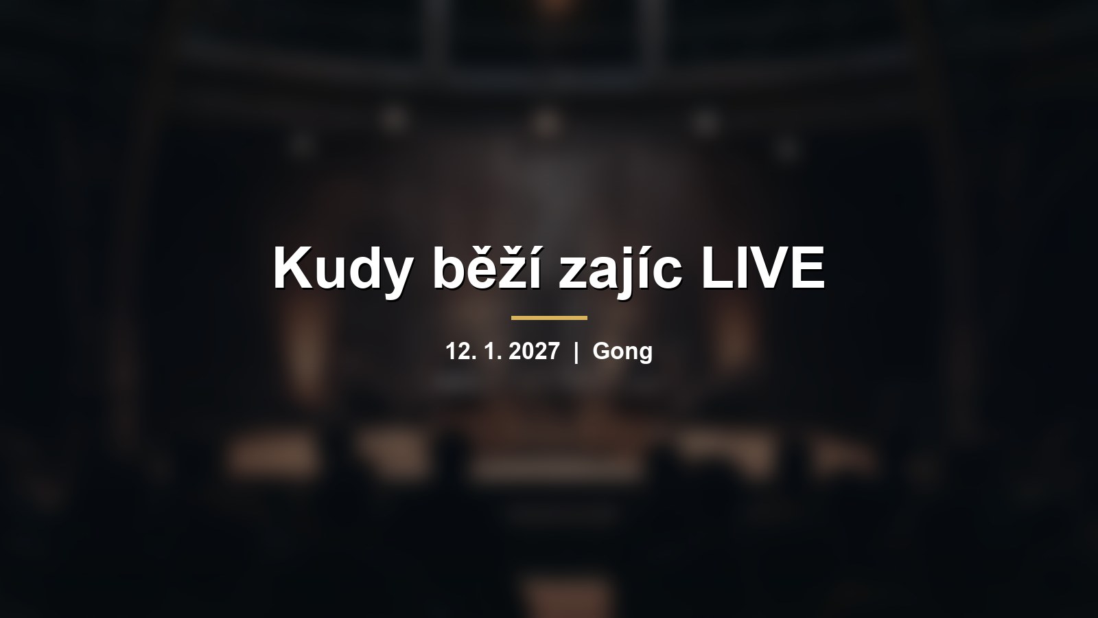 Rozmazané pódium s mikrofony v kruhovém sále s nápisem Kudy běží zajíc LIVE