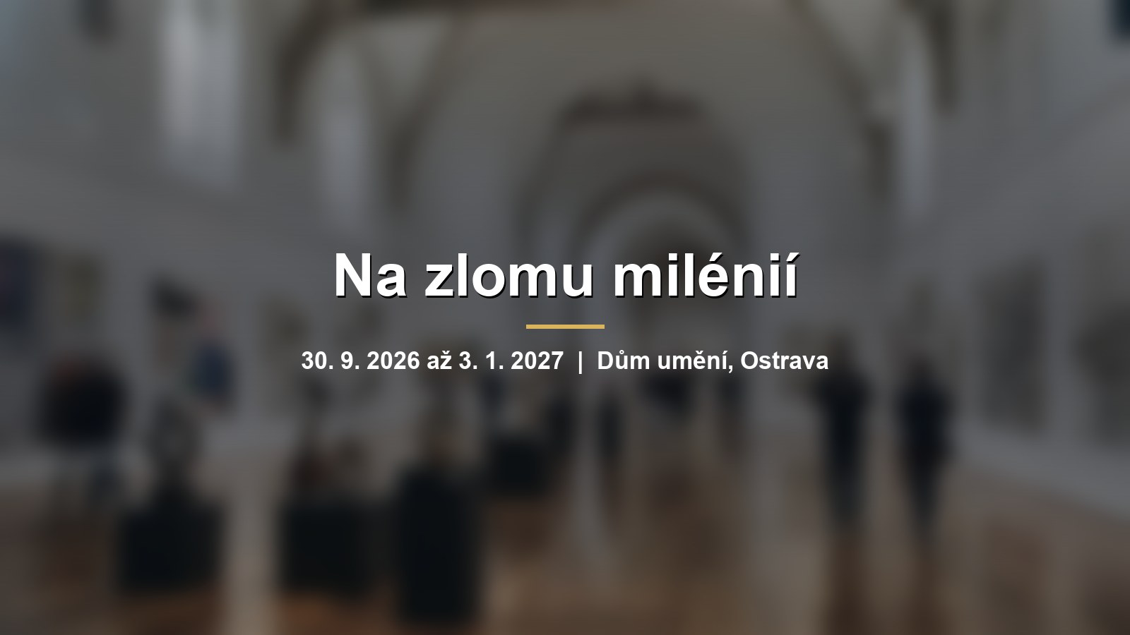 Rozmazaný výstavní sál s obrazy a objekty na bílých stěnách s nápisem Na zlomu milénií